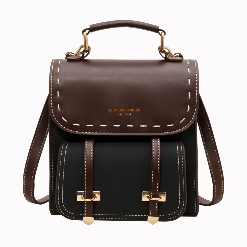 Small Vintage Black And Brown Backpack With Straps On The Front And Handle On A Very Light Grey Background.