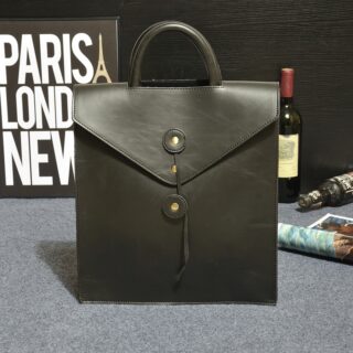 Sac à dos enveloppe noir avec un fond gris et des objets derrière le sac