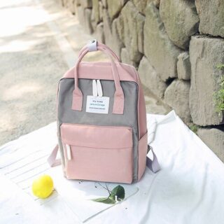 Grey and pink 15 inch canvas backpack with stone wall background