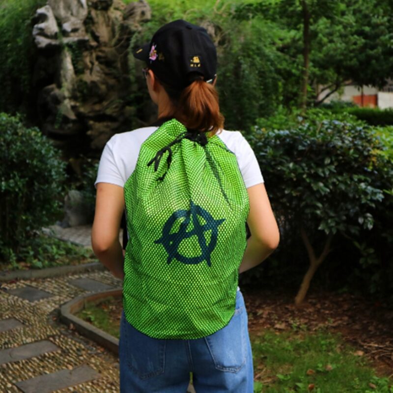 Green Mesh Beach Bag With A Garden Background And A Woman Carrying The Bag